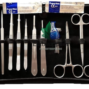 May include: A black zippered case containing a stainless steel dissection kit with various scalpels, forceps, scissors, and probes. Two sterile surgical blade packets are positioned at the top, and a logo with a blue flask is visible in the center.