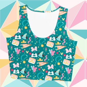 May include: Teal crop top featuring a repeating pattern of cartoon elements such as Mickey Mouse ears, bows, crowns, and the text "Parks Runner" and "Run Walk Run". The top has a scoop neck and is sleeveless.