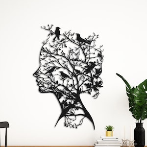 Puede incluir: Arte de pared de metal negro con la silueta de la cara de una mujer con un árbol que crece de su cabeza. El árbol está lleno de pájaros pequeños.