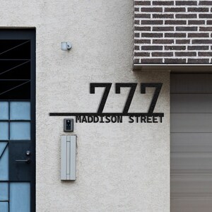 May include: A modern house with a black metal door and a garage door. The house number is 777 Madison Street.