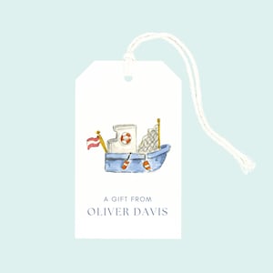 May include: A white gift tag with a watercolor illustration of a blue boat with a red and white flag, life preserver, and fishing net. The tag reads "A Gift From Oliver Davis" in blue text, with a white string attached.