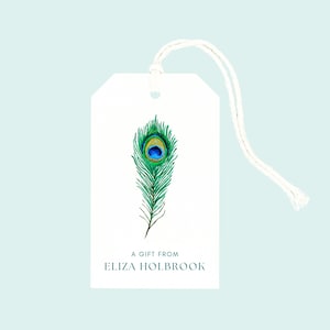 May include: White gift tag with a watercolor peacock feather design in shades of green, blue, and yellow. The tag includes the text "A GIFT FROM ELIZA HOLBROOK" in a teal font, and is attached to a white string.