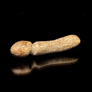 Könnte beinhalten: Ein glatter, hellbrauner, abgerundeter Stein mit einer strukturierten Oberfläche. Der Stein ist in Form eines langen, dünnen, abgerundeten Stabes mit einem abgerundeten Ende geformt.
