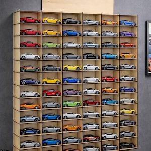 May include: A wall-mounted wooden display shelf with six vertical columns and ten horizontal rows, featuring individual compartments for toy cars. The unit is filled with various miniature model cars in diverse colors including red, yellow, blue, and silver.