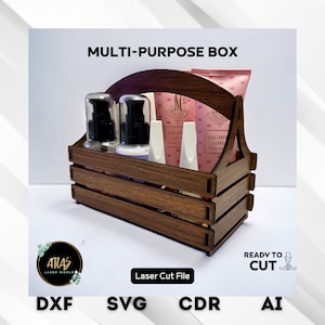 Op de afbeelding: Een houten doos met een handvat, ontworpen om flessen en buizen te bevatten. De doos is bruin met een houtnerfpatroon. De doos is gelabeld "MULTI-PURPOSE BOX" en heeft de tekst "Laser Cut File" eronder. De doos is omgeven door verschillende flessen en buizen, waaronder een roze buis met het label "MACAROL LOVE HAND CREAM".