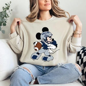 a woman sitting on a couch holding a mickey mouse shirt