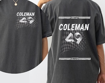 Puede incluir: Una camiseta gris de gran tamaño con un diseño gráfico blanco que presenta el texto "Coleman 49" y un patrón de bandera a cuadros. El texto "START" y "FINISH" también están incluidos en el diseño.