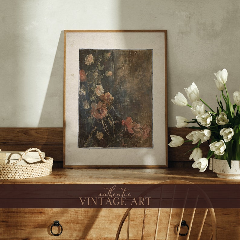 May include: A framed vintage art print featuring a floral still life painting with pink and white flowers on a brown background. The frame is made of wood and has a light brown finish.