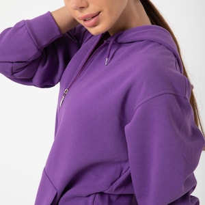 May include: A purple hooded sweatshirt with a zip fastening. The sweatshirt has a kangaroo pocket and a relaxed fit.