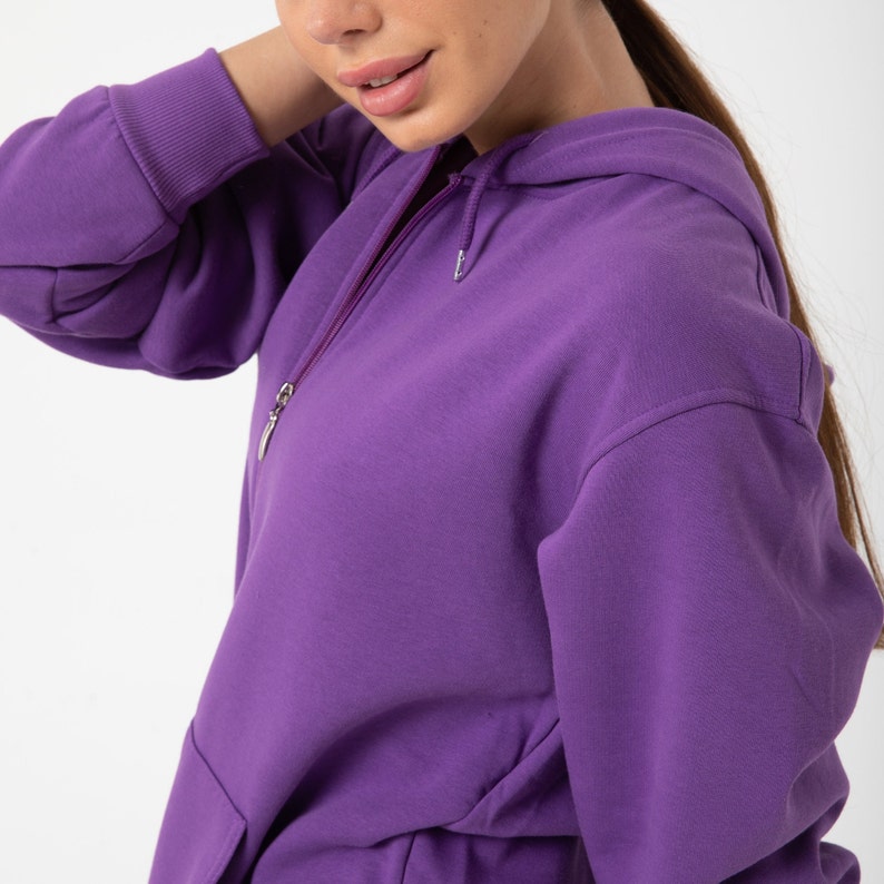 May include: A purple hooded sweatshirt with a zip fastening. The sweatshirt has a kangaroo pocket and a relaxed fit.