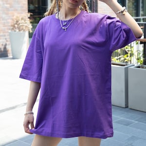 Puede incluir: Una camiseta de color morado de gran tamaño con cuello redondo.