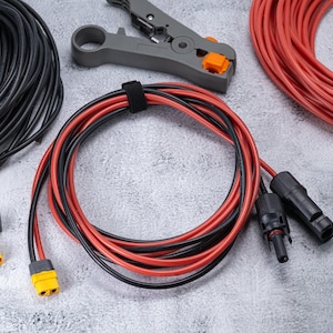 Puede incluir: Primer plano de suministros de cableado eléctrico, que incluyen carretes de cable negro y rojo, crimpadoras de cable y conectores de cable negro y amarillo.