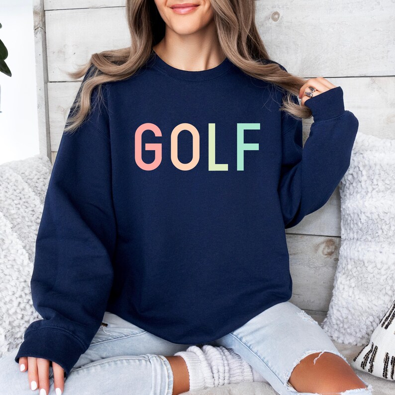 Pode incluir: Uma camisa de moletom azul marinho com a palavra "GOLF" impressa em cores do arco-&iacute;ris no peito.
