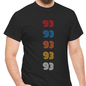 May include: Black t-shirt with a vertical row of five numbers, each '93' in a different color: red, blue, orange, yellow, and white.