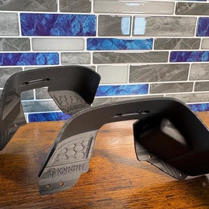 May include: Two black 3D-printed automotive fender flares featuring a textured honeycomb pattern on the side panels. Each piece displays the embossed text KNIGHT along with a small helmet icon, and includes pre-drilled circular mounting holes.
