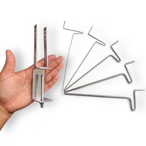 May include: A silver metal clamp with a screw adjustment and six silver metal hooks. The clamp is designed to attach to a table or other surface.