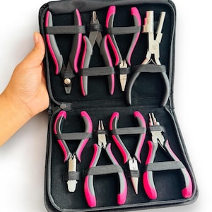 May include: A set of eight jewelry making pliers in a black zippered case. The pliers have pink handles and are arranged in two rows.