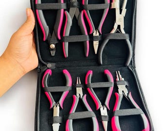 May include: A set of eight jewelry making pliers in a black zippered case. The pliers have pink handles and are arranged in two rows.