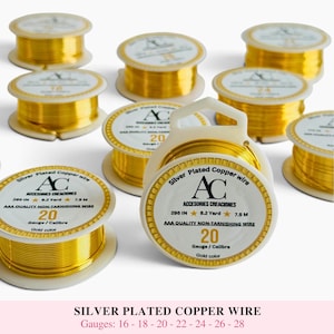 May include: Multiple spools of gold-colored silver-plated copper wire arranged in a group. Each white plastic spool features a label with the AC Accesories Creaciones logo, the wire gauge, and length specifications including 295 inches and 7.5 meters.