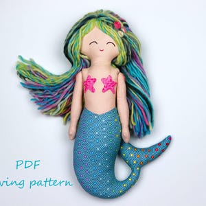 May include: A PDF sewing pattern for a mermaid doll with a blue and green tail, pink starfish embellishments, and long, colorful yarn hair.