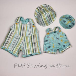 May include: Two pairs of baby overalls and two matching hats. One set is striped in green, blue, and white. The other set is light blue with animal graphics. The overalls have button closures.