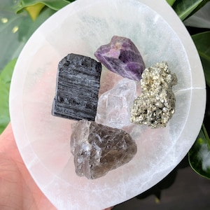 May include: A white selenite charging plate with a variety of crystals including black tourmaline, amethyst, clear quartz, smoky quartz, and pyrite.
