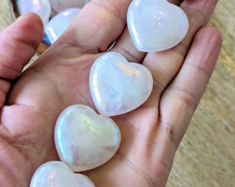 May include: A collection of iridescent white heart-shaped crystals. The crystals are smooth and polished, with a subtle shimmer.