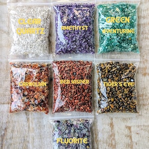 May include: Eight small bags of tumbled gemstones, each labelled with the type of stone: Clear Quartz, Amethyst, Green Aventurine, Carnelian, Red Jasper, Tiger's Eye, and Fluorite.