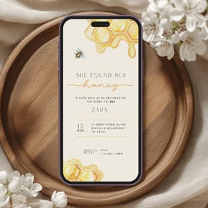 May include: A digital phone screen displaying a honey-themed bridal shower invitation with a watercolor illustration of a honeycomb and dripping honey. The invitation reads "She found her honey" and includes the bride-to-be's name, Zara, the date, March 15th, and the location, 11 Honeycomb Haven, Beeville Boulevard, TX 78102. RSVP information is provided with the name Lola and a phone number.