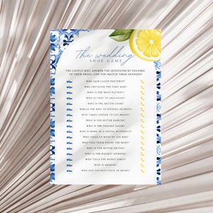 May include: A blue and white tiled background with a lemon illustration. The text "The Wedding Shoe Game" is at the top of the page. The game asks a series of questions about a couple, such as "Who said I love you first?" and "Who is the better cook?" Players answer the questions by holding up their shoes.