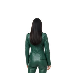 May include: A green leather jacket and matching pants set. The jacket has a tailored fit with a structured collar and button details. The pants are fitted. The model is facing away from the camera, with long black hair.