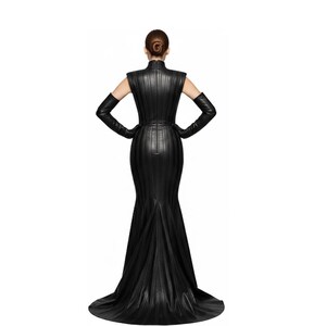 Puede incluir: Un vestido negro largo hasta el suelo, con cuello alto y mangas largas. El vestido presenta paneles verticales y una falda acampanada. La modelo lleva guantes largos negros y tiene las manos en las caderas. El vestido es de un material brillante.