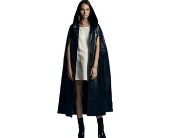 May include: A woman wearing a black leather hooded cape with a white dress underneath. She is wearing black boots.