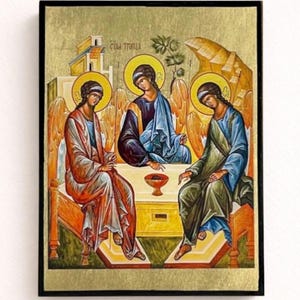 Puede incluir: Icono que representa tres figuras con halos, sentadas alrededor de una mesa. Las figuras visten túnicas en tonos rojos, azules y verdes. El fondo presenta pan de oro y elementos arquitectónicos. El texto "CTAA TPИИЦA" es visible.