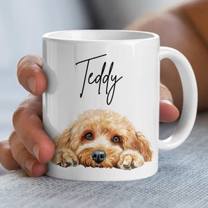 May include: White ceramic mug featuring a watercolor illustration of a golden-brown dog with the name "Teddy" in black script. The dog's head and paws are visible, creating a charming design.