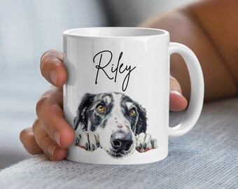 May include: White ceramic mug with a black and white dog peeking over the rim. The dog's name, "Riley", is written in black cursive on the mug.