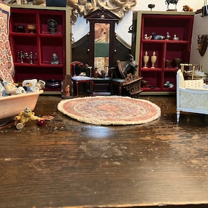 May include: A miniature dollhouse room featuring a pink bathtub, a white settee, a round rug, and several small wooden cabinets filled with miniature furniture and accessories.