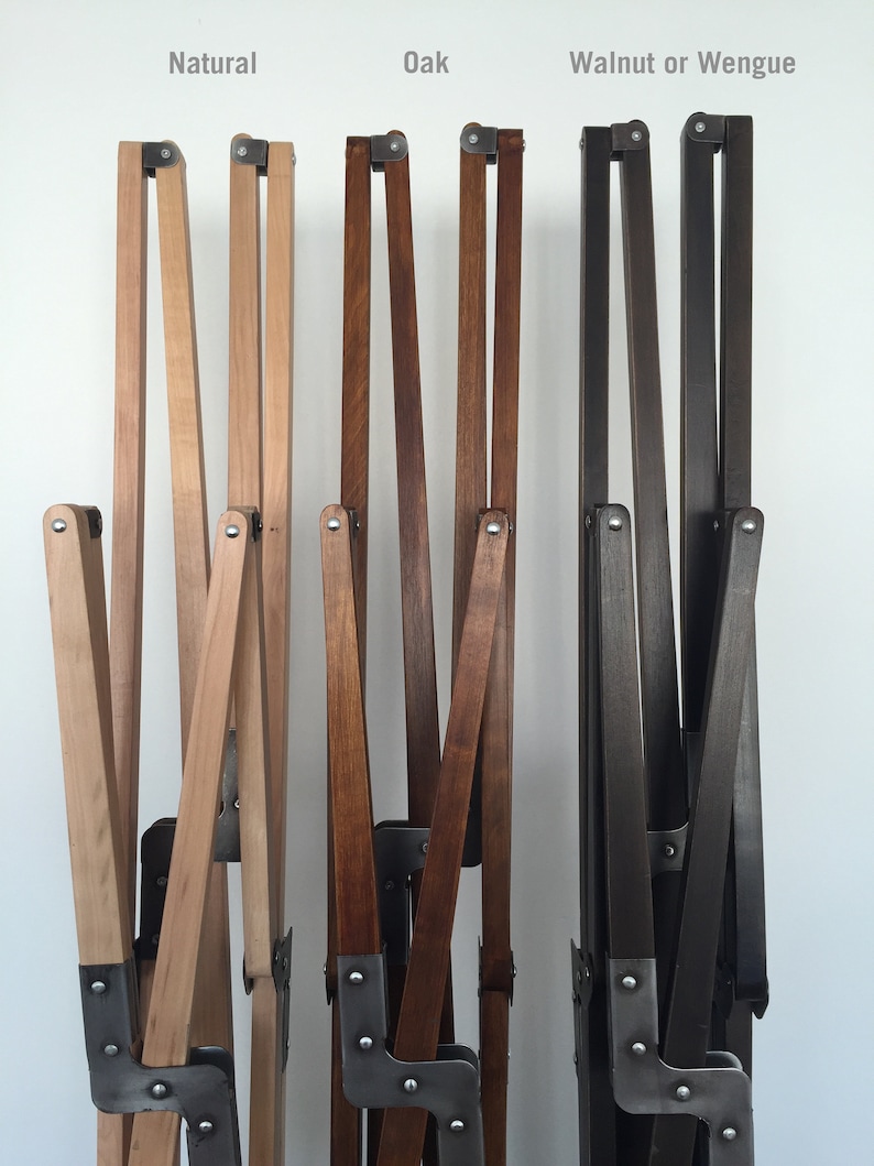 May include: Three wooden chair frames in different wood finishes: natural, oak, and walnut or wenge. The frames are made of wood and metal and are folded up.