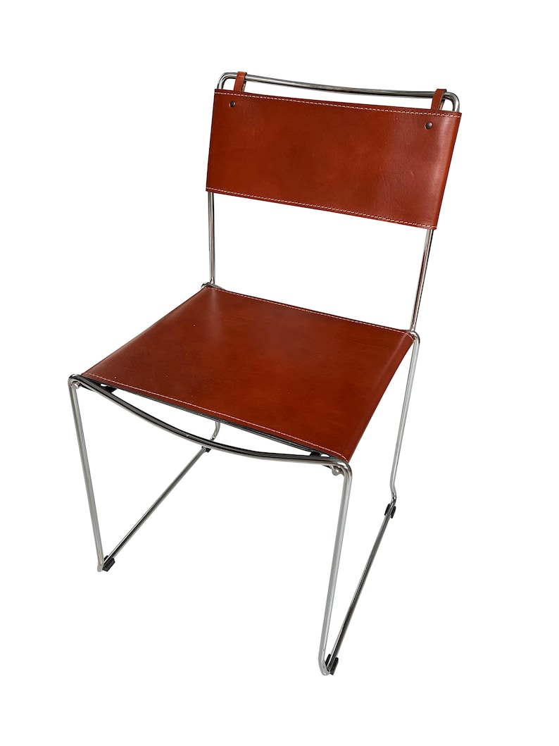May include: A modern chair with a brown leather seat and backrest. The chair has a minimalist design with a chrome-colored metal frame. The leather is stitched with white thread. The chair is suitable for indoor use.