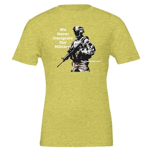 May include: A yellow t-shirt with a graphic of a soldier holding a rifle. The text "We Never Denigrate Our Military" is printed on the shirt. The website "ThePowerOfU.com" is printed at the bottom of the shirt.