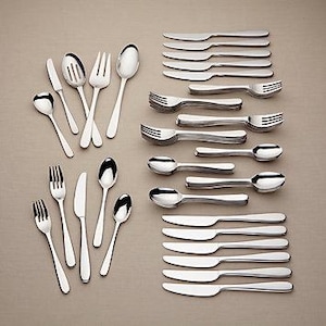 May include: A collection of stainless steel silverware, including forks, knives, and spoons, arranged on a neutral-toned surface. The set includes various sizes and styles of utensils, suitable for a complete dining setting.