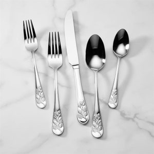 May include: A set of five silver-plated flatware pieces with a floral design. The set includes a knife, fork, and three spoons.