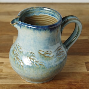 May include: A set of three ceramic mugs with a speckled, matte finish in cream, light grey, and dark grey. Each mug has a simple, minimalist design, ideal for coffee or tea.