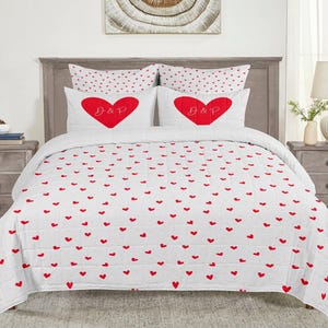 May include: White and red heart patterned quilt set with two pillowcases. The pillowcases feature a large red heart with the initials "D & P" in white.