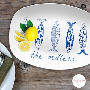 May include: White oval serving platter with a blue and white fish design and the text "the millers". The platter is decorated with lemons and green leaves.