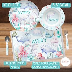 May include: A blue and green personalized children's placemat with a whale, narwhal, octopus, and other sea creatures. The placemat is 12 inches by 18 inches and is double-sided. It comes with a matching 10-inch plate, 8.5-inch bowl, and a custom spoon and fork.