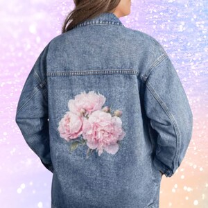 the back of a person wearing a denim jacket with a floral design on the back.