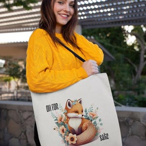 A woman wearing a yellow sweater is holding a white tote bag with a fox graphic and the text "Oh for sah!" printed on it.