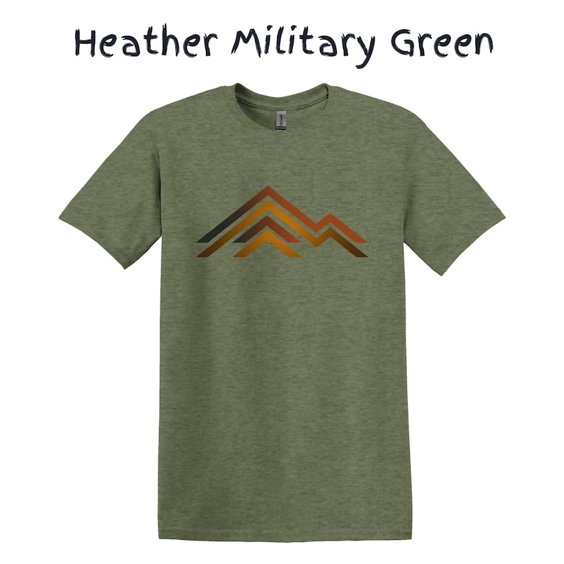 Puede incluir: Camiseta verde militar jaspeado con un gr&aacute;fico de monta&ntilde;a en tonos marrones y naranjas. La camiseta es de estilo cuello redondo y manga corta. El texto "Heather Military Green" est&aacute; encima de la camiseta.