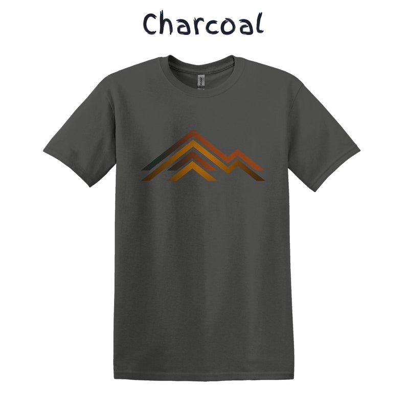 Puede incluir: Camiseta de color carb&oacute;n con un dise&ntilde;o de cordillera en tonos naranja, marr&oacute;n y gris. La palabra "Charcoal" est&aacute; escrita en cursiva encima de la camiseta.
